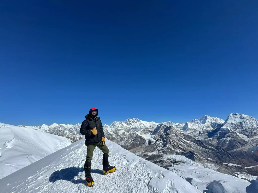 Climber standing on Mera Peak summit with panoramic Himalayan view