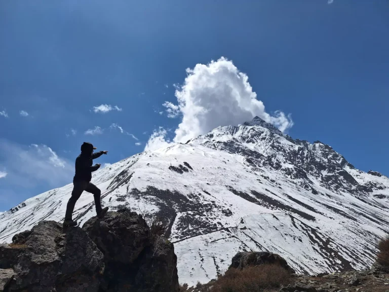 Trekker pointing towards snow-covered mountain peak along the Manaslu Circuit Trail