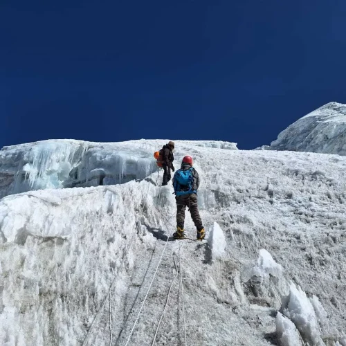 Trekker climbing Lobuche Peak under a clear open sky using a rope on the steep icy slope Trekker climbing Lobuche Peak under a clear open sky, using a rope on the steep icy slope