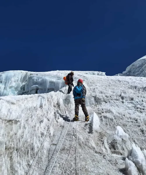 Trekker climbing Lobuche Peak under a clear open sky using a rope on the steep icy slope Trekker climbing Lobuche Peak under a clear open sky, using a rope on the steep icy slope