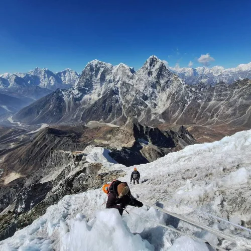 Trekker climbing Lobuche Peak with rope support against a backdrop of snowy mountain terrain Trekker climbing Lobuche Peak with rope support against a backdrop of snowy mountain terrain